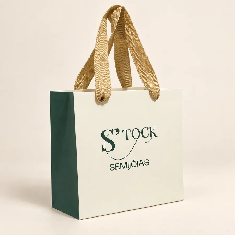 Sacola de papel personalizada creme e verde escuro com alça dourada e a marca S'TOCK Semijóias impressa.